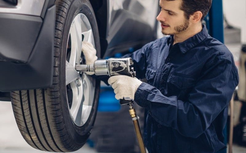 Mechanic balancing a large tire at Fremont Motor Cody Ford